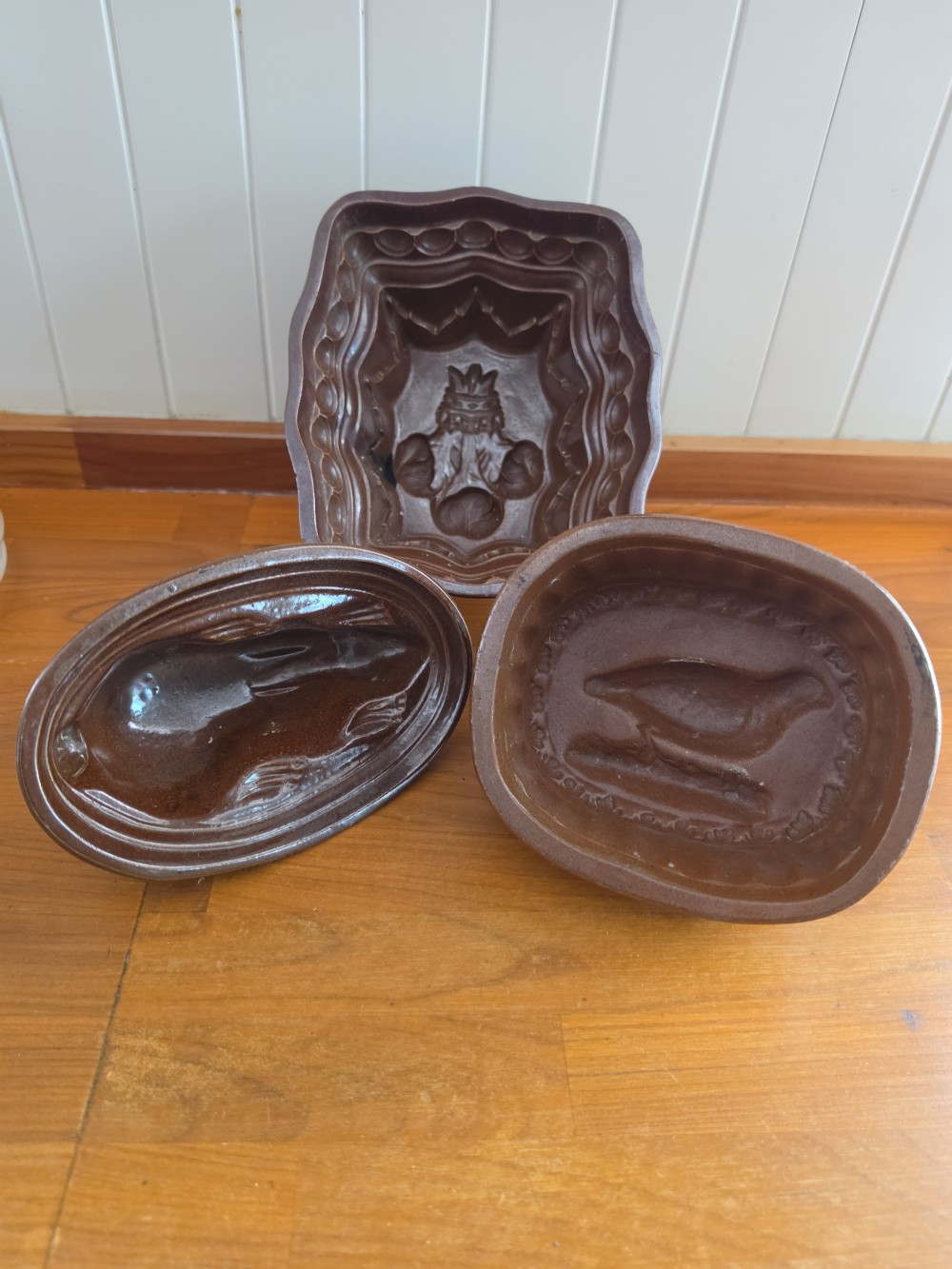 A set of three 19th-century brown stoneware jelly moulds featuring interior relief carvings of a crown crest, a rabbit, and a bird. View III