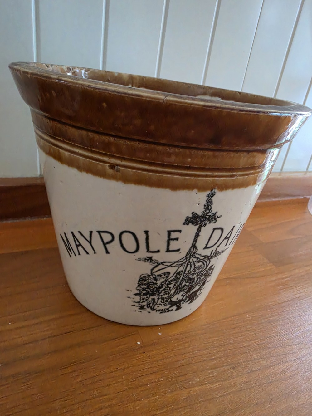 A Victorian cream stoneware dairy crock featuring a brown glazed rim and black transfer-printed Maypole Dairy lettering and illustration. View V