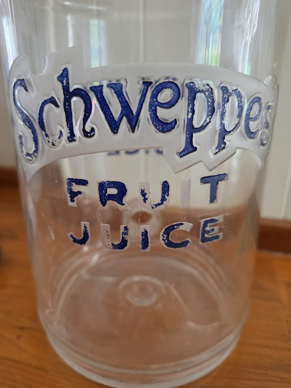 A large clear glass Schweppes fruit juice dispenser featuring printed lettering, a pointed finial lid, and a metal tap at the base. View VI