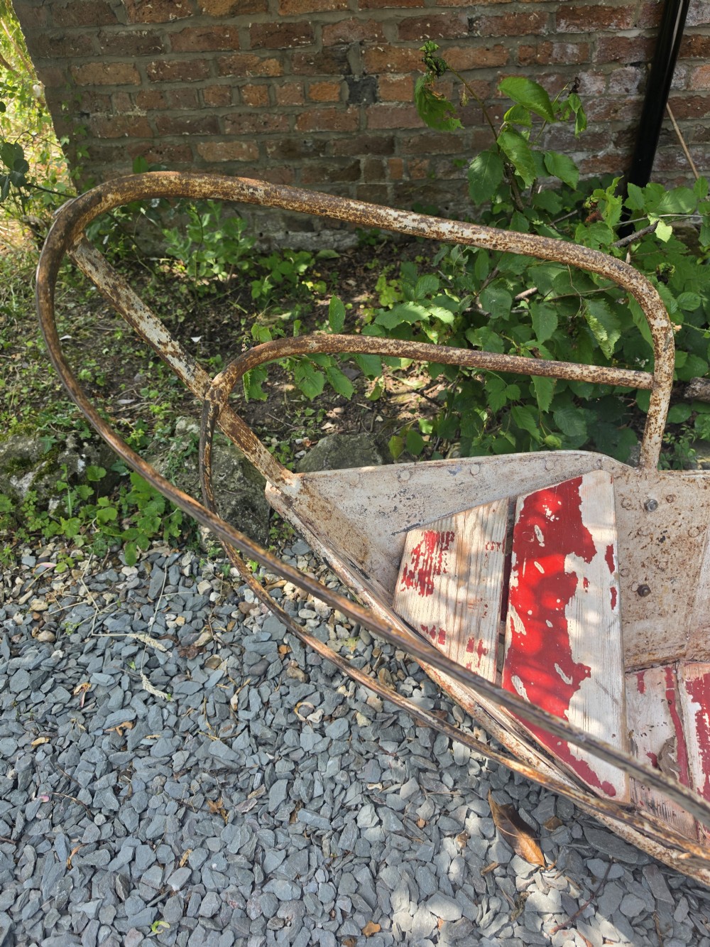 A late nineteenth-century riveted metal boat fairground ride with curved tubular iron safety railings and weathered cream and red painted panels. View V