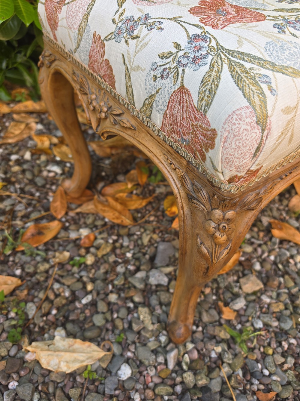 A long 19th-century stool crafted from carved walnut with cabriole legs and upholstered in a floral pattern fabric. View II