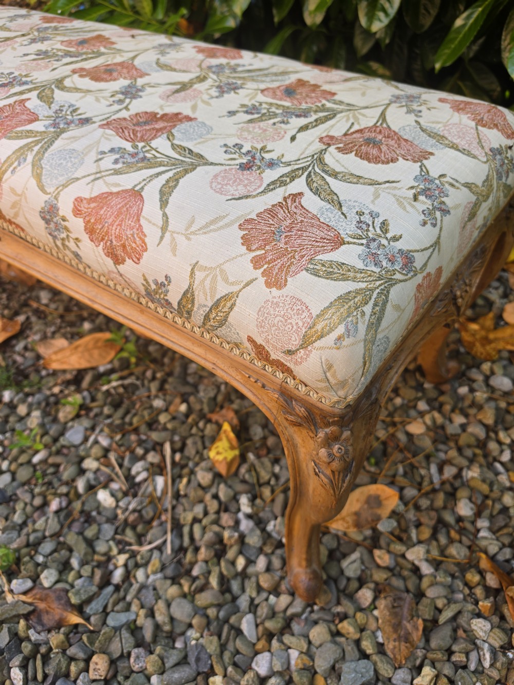 A long 19th-century stool crafted from carved walnut with cabriole legs and upholstered in a floral pattern fabric. View III