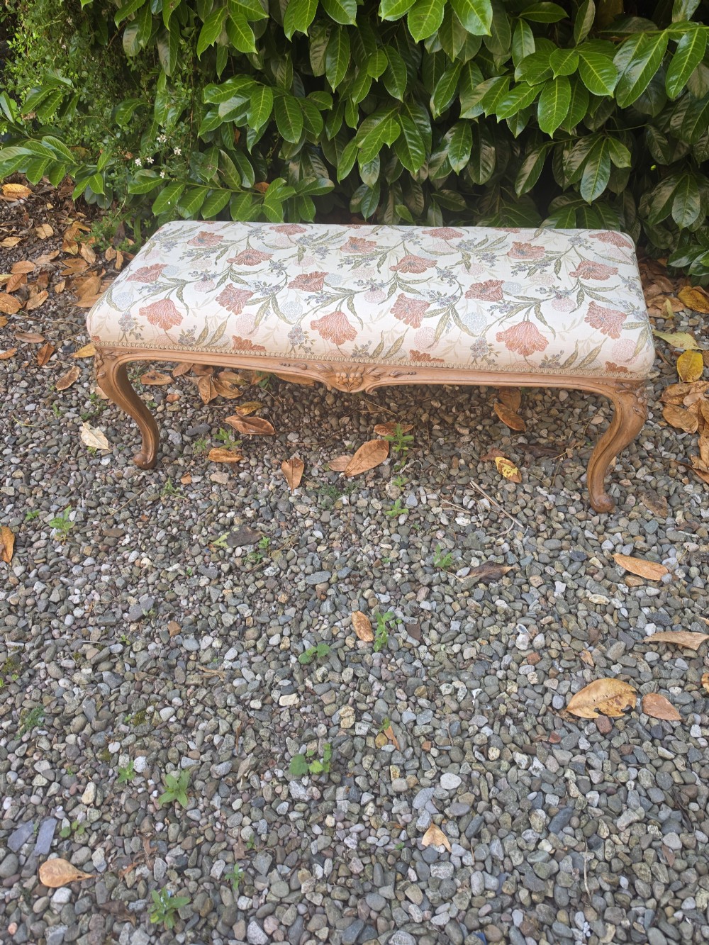 A long 19th-century stool crafted from carved walnut with cabriole legs and upholstered in a floral pattern fabric. View VI