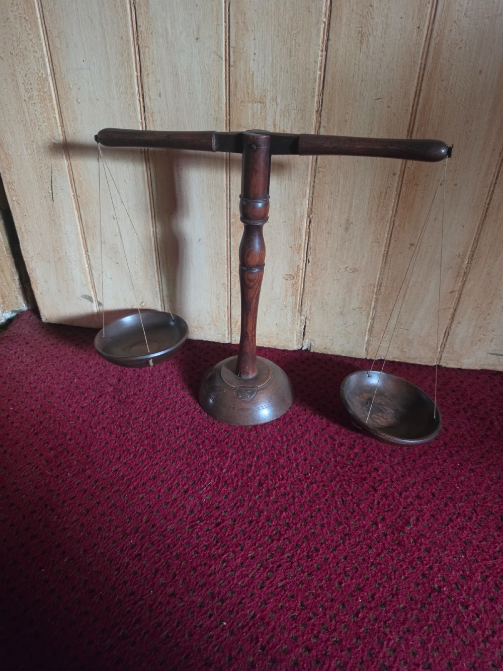 A 19th-century turned dark wood treen balance scale set with a central column, horizontal crossbar, and two suspended wooden pans.