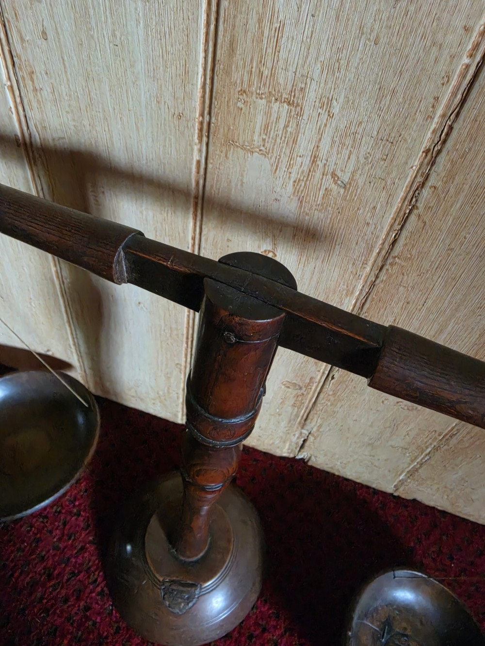 A 19th-century turned dark wood treen balance scale set with a central column, horizontal crossbar, and two suspended wooden pans. View IV