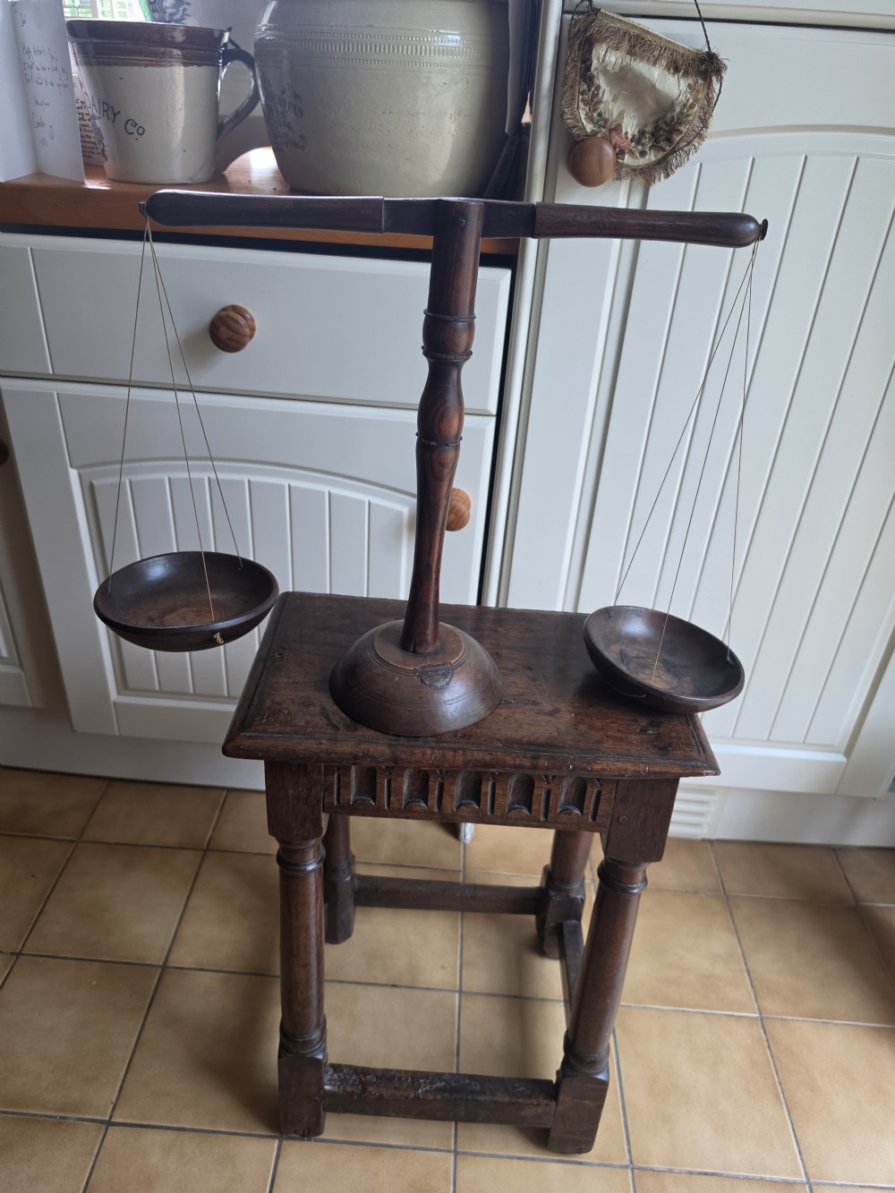 A 19th-century turned dark wood treen balance scale set with a central column, horizontal crossbar, and two suspended wooden pans. View VII