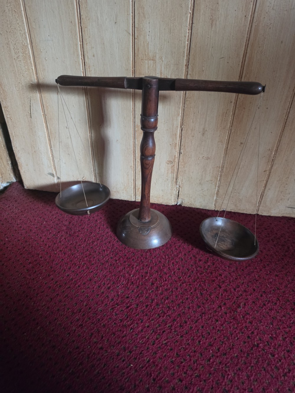 A 19th-century turned dark wood treen balance scale set with a central column, horizontal crossbar, and two suspended wooden pans. View VIII