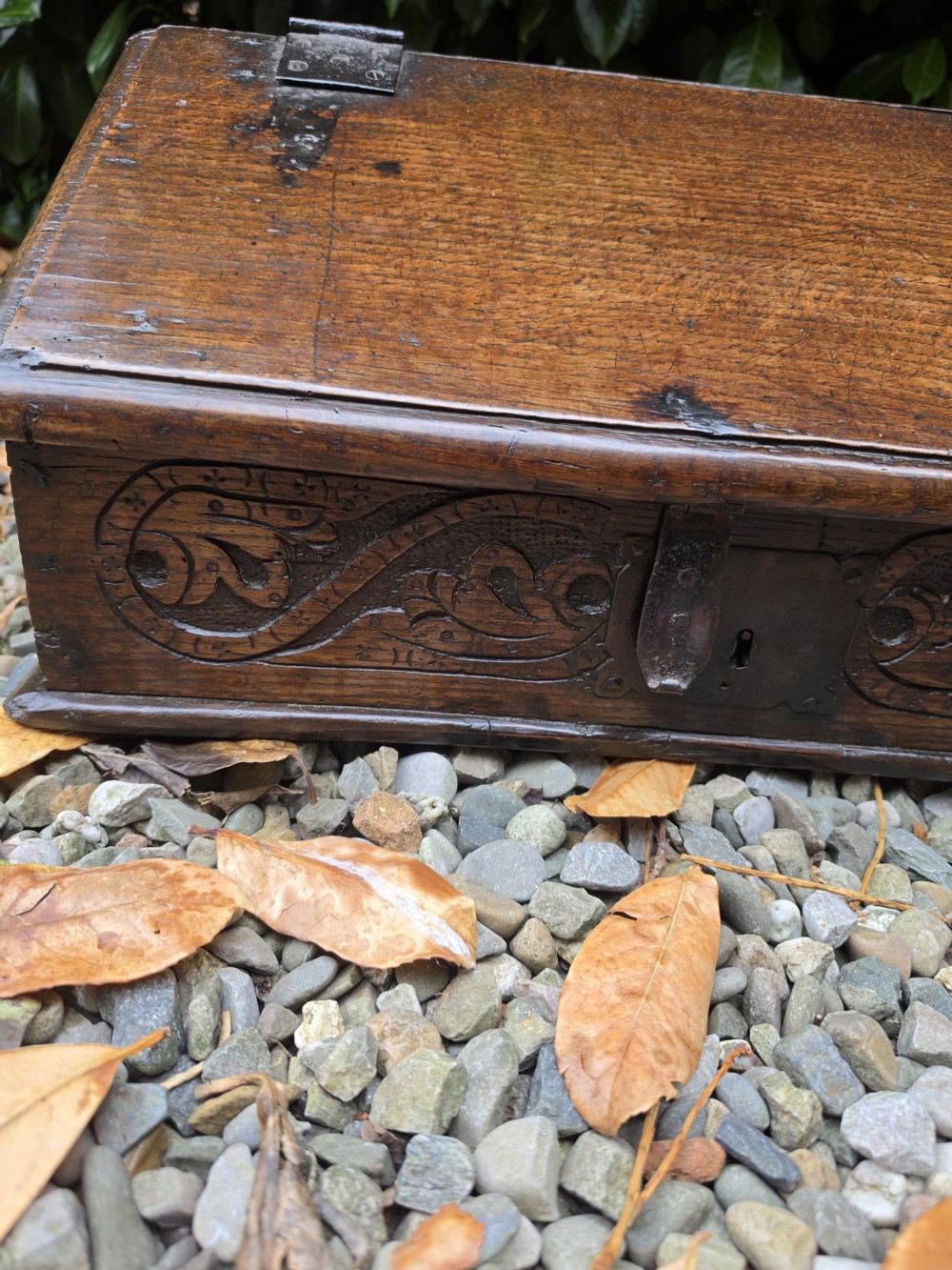 A late seventeenth-century dark oak slant-front Bible box featuring hand-carved scrollwork on the front panel and dark iron strap hinges. View III