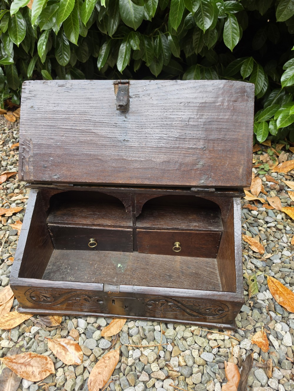 A late seventeenth-century dark oak slant-front Bible box featuring hand-carved scrollwork on the front panel and dark iron strap hinges. View IV