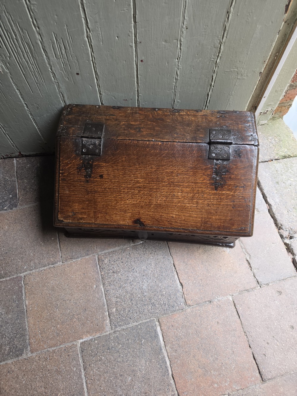 A late seventeenth-century dark oak slant-front Bible box featuring hand-carved scrollwork on the front panel and dark iron strap hinges. View V