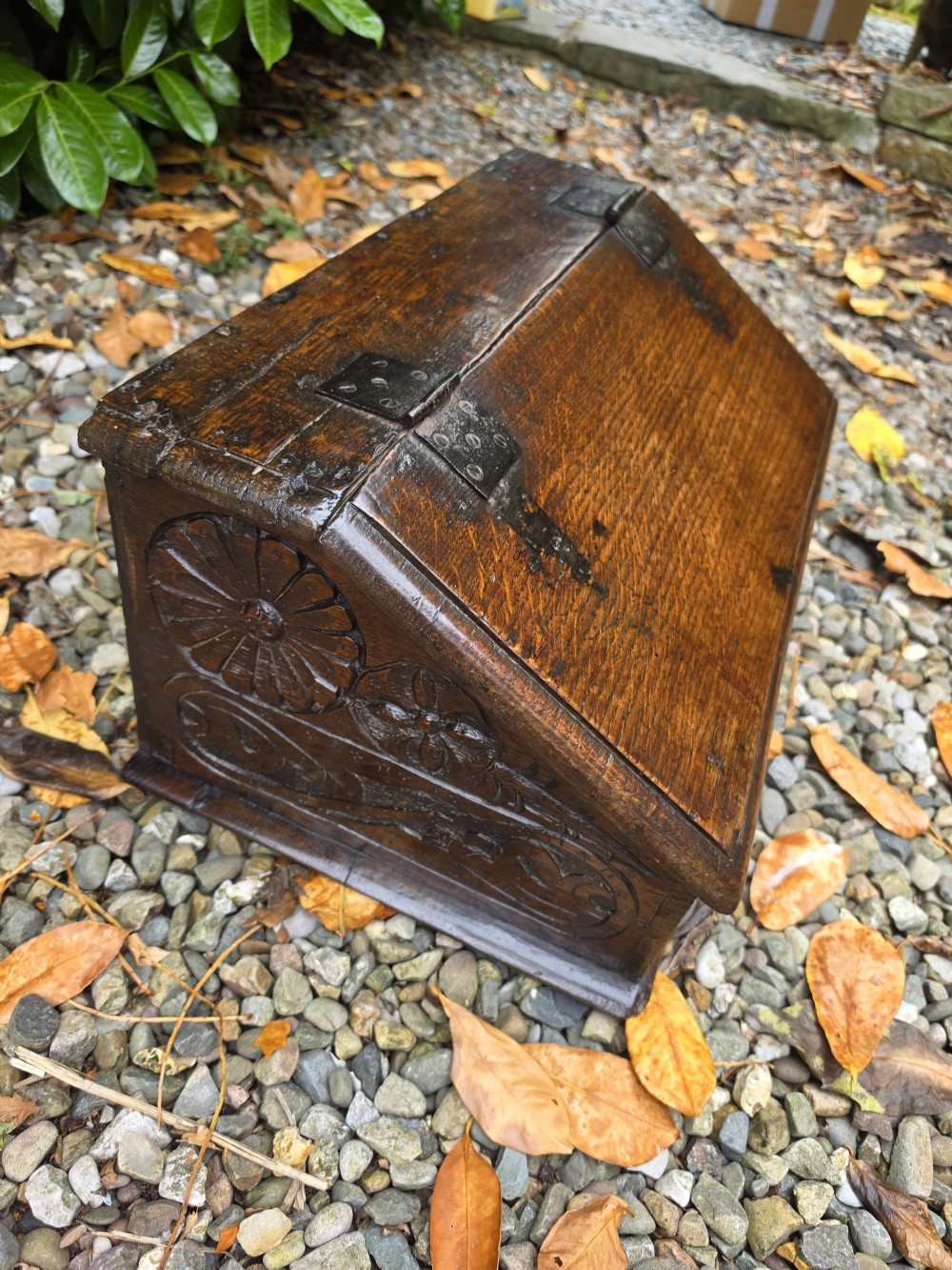 A late seventeenth-century dark oak slant-front Bible box featuring hand-carved scrollwork on the front panel and dark iron strap hinges. View VI