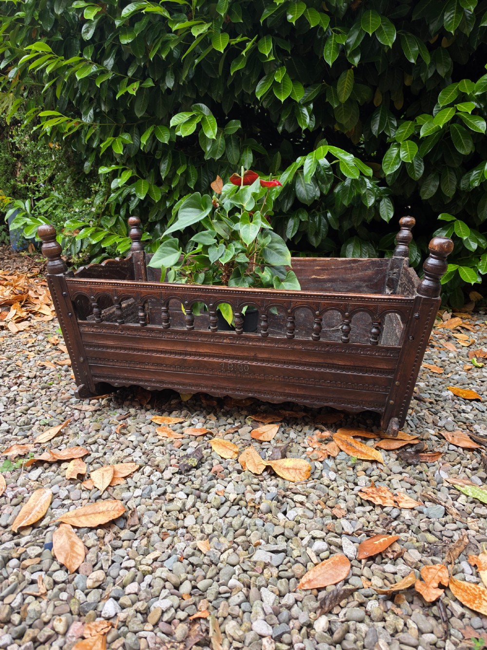 A 17th-century carved dark oak and fruitwood rocking cradle featuring turned corner finials and a spindle gallery side rail. View II