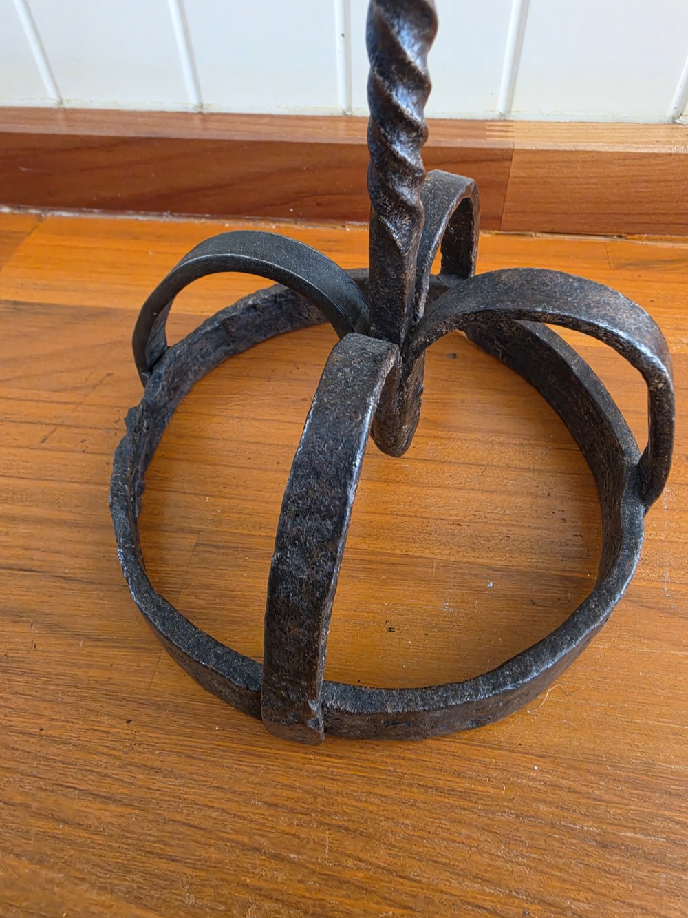 A hand-forged wrought iron rushlight holder featuring a central spring nip clamp, two candle sockets on curved side arms, a twisted stem, and a hoop base. View III