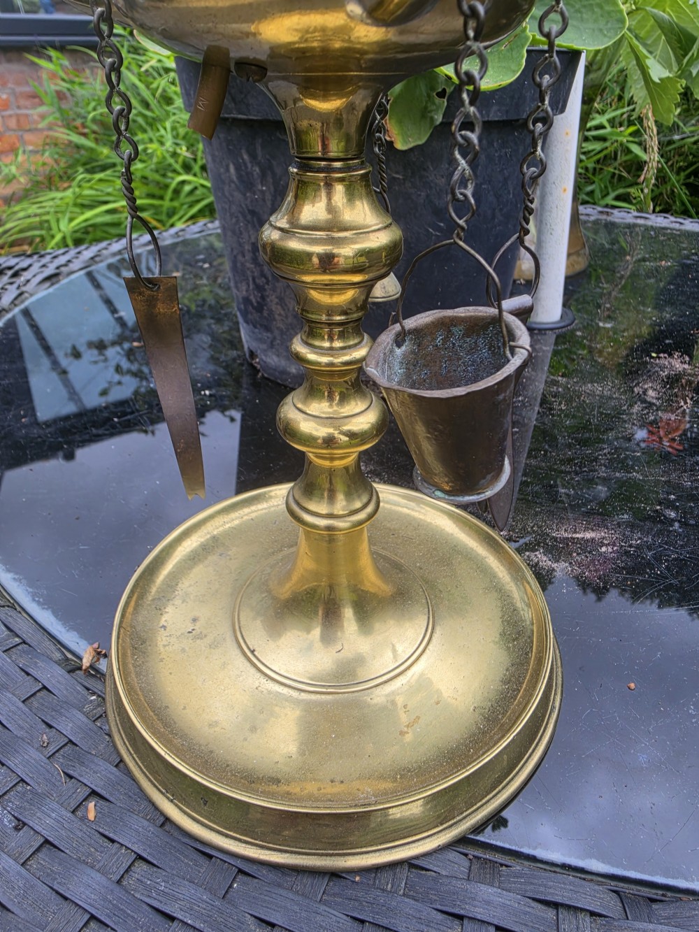 A 19th-century brass student lamp with a circular stepped base, central turned stem with loop handle, three candle sleeves, and miniature brass tools suspended from chains. View II