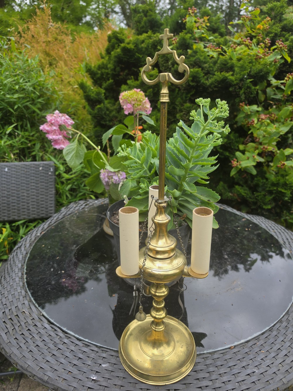 A 19th-century brass student lamp with a circular stepped base, central turned stem with loop handle, three candle sleeves, and miniature brass tools suspended from chains. View III