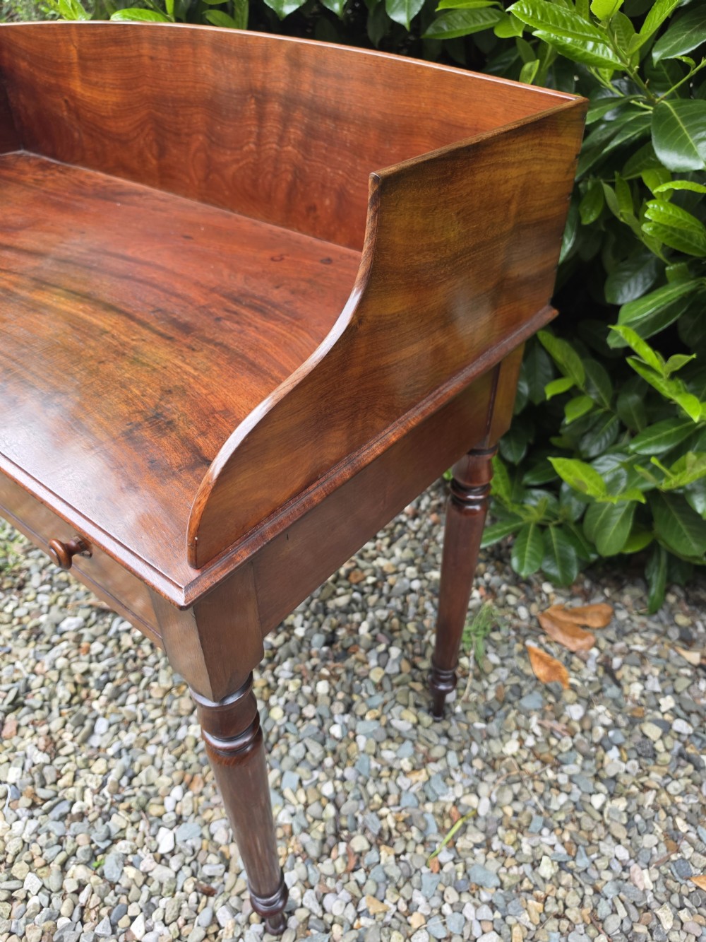 An antique Georgian mahogany side table featuring two drawers with turned wooden knobs, four turned legs, and a high curved gallery back. View III