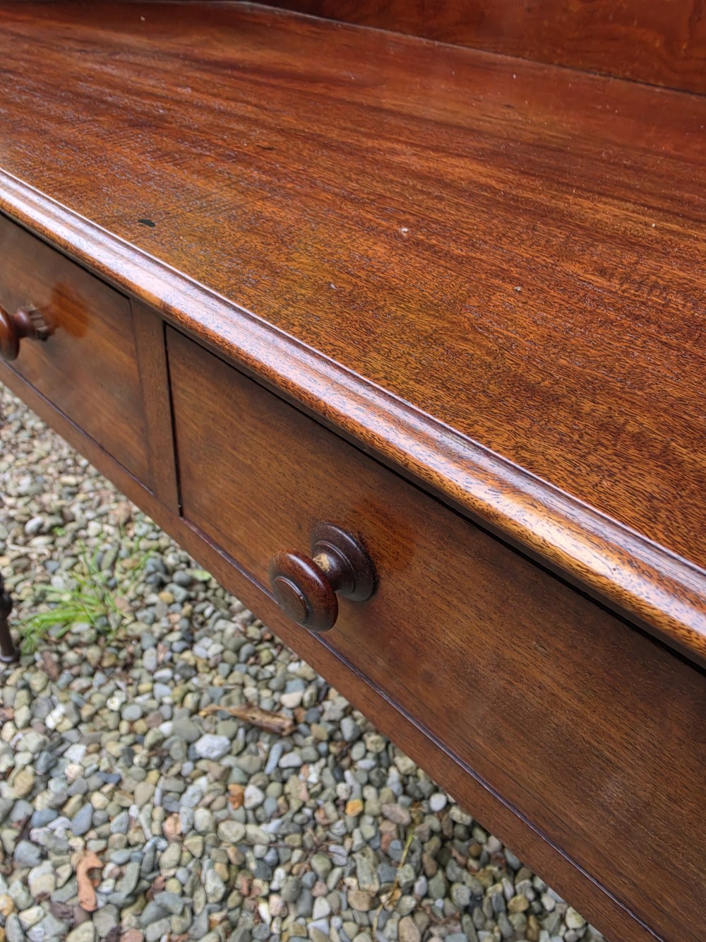 An antique Georgian mahogany side table featuring two drawers with turned wooden knobs, four turned legs, and a high curved gallery back. View V