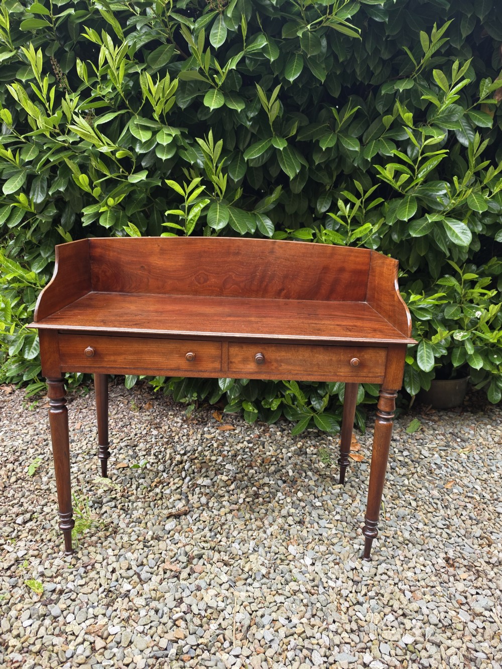 An antique Georgian mahogany side table featuring two drawers with turned wooden knobs, four turned legs, and a high curved gallery back. View VI