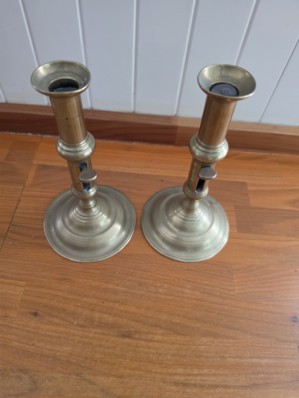 A pair of mid-18th-century seamed brass candlesticks featuring turned stems, slide ejector mechanisms, and circular stepped bases. View V