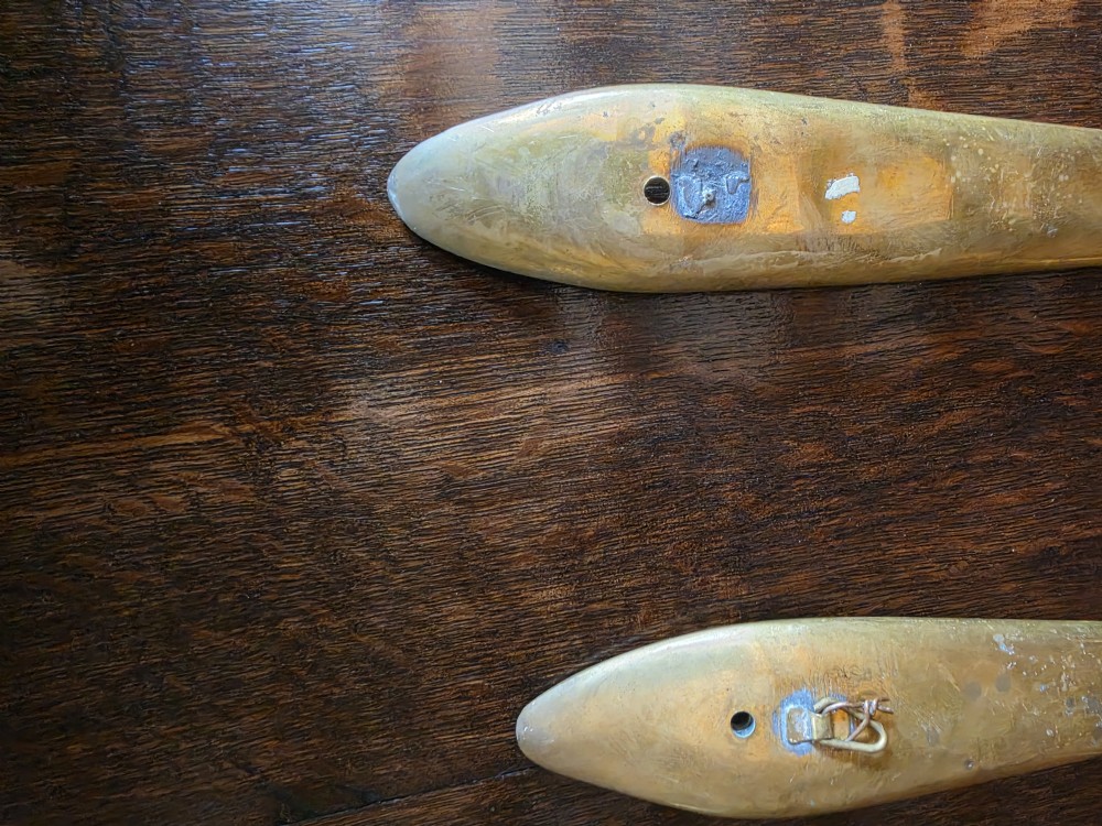 A pair of vintage brass wall plaques shaped as a large spoon and fork with pre-drilled mounting holes at the top of the handles. View V