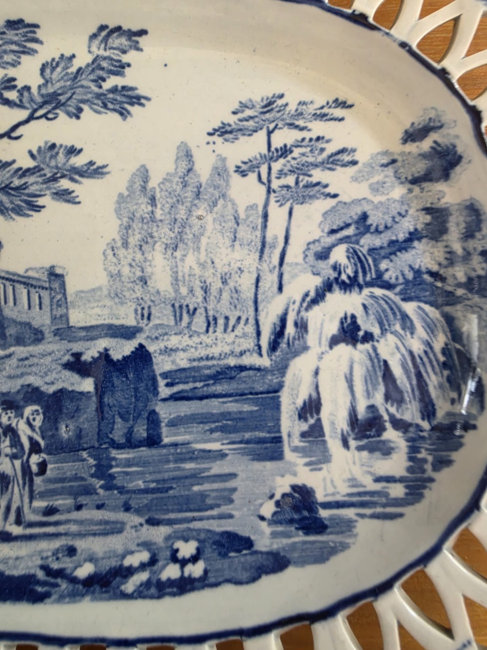 An early 19th-century oval blue and white earthenware platter with a pierced reticulated rim and central pastoral landscape scene. View IV