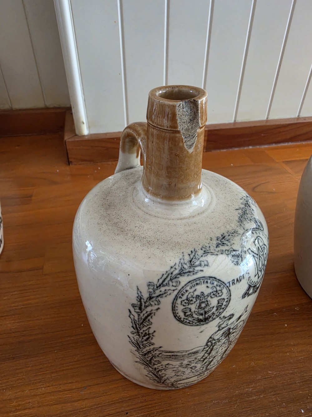 A set of four 19th-century cream stoneware advertising whisky flasks featuring black transfer-printed text and brown glazed spouts. View III