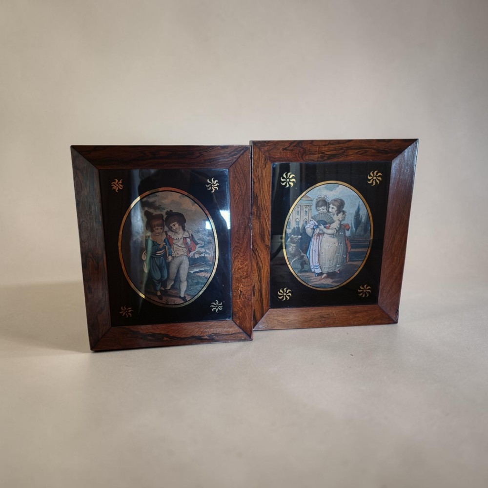 A pair of square rosewood picture frames featuring oval 19th-century prints of children set within black reverse-painted glass mounts with gold motifs. View VI