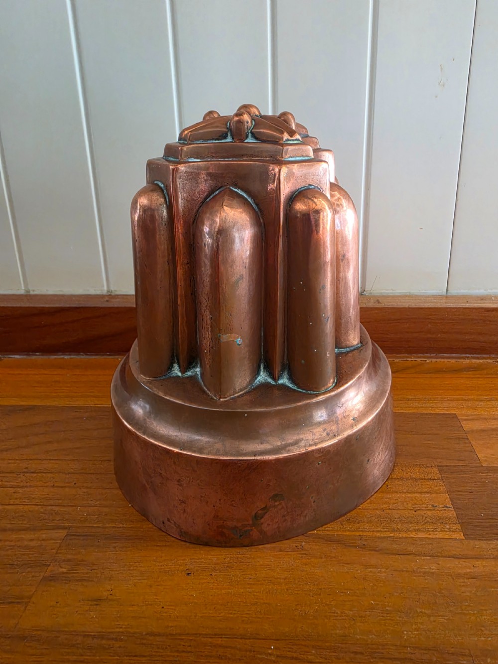 A large 19th-century copper jelly mould featuring a tiered architectural design with vertical fluted arches and a patinated finish.