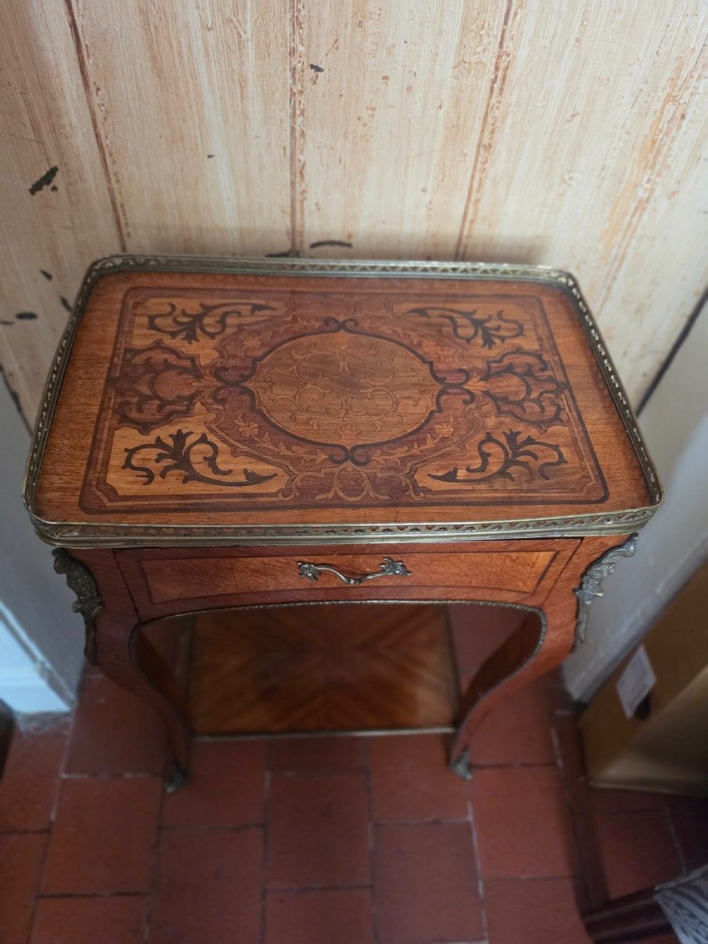 A 19th-century French style marquetry inlaid side table featuring a pierced brass gallery rim, single drawer, lower tier shelf, and cabriole legs with brass mounts.