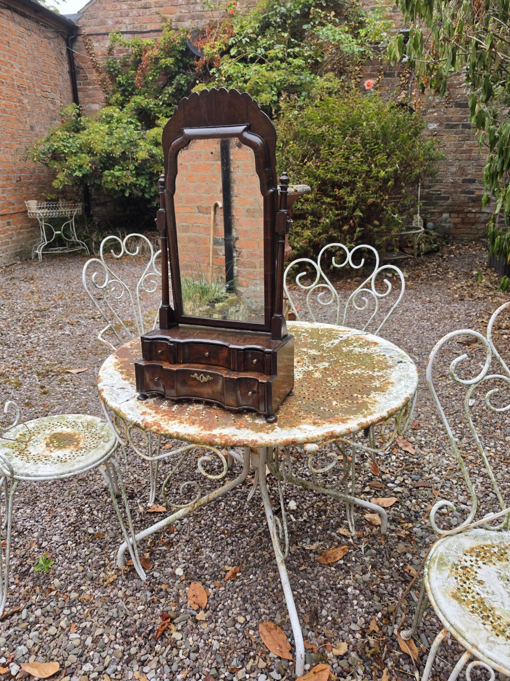 An eighteenth-century George I patinated dark walnut toilet mirror featuring an arched adjustable swing glass over a two-tier serpentine drawer base with brass hardware. View VII