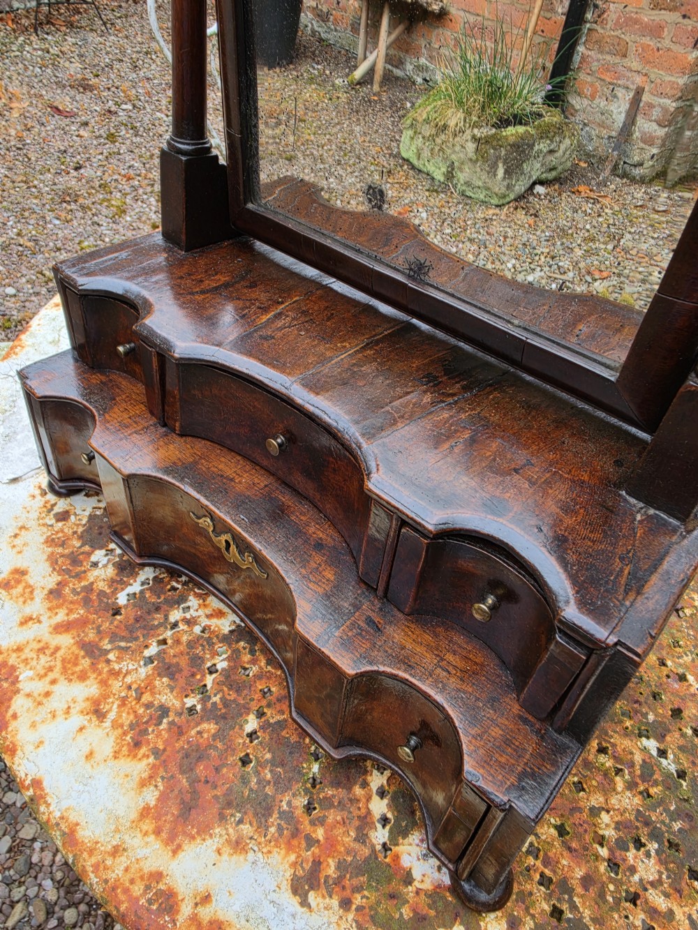 An eighteenth-century George I patinated dark walnut toilet mirror featuring an arched adjustable swing glass over a two-tier serpentine drawer base with brass hardware. View IX