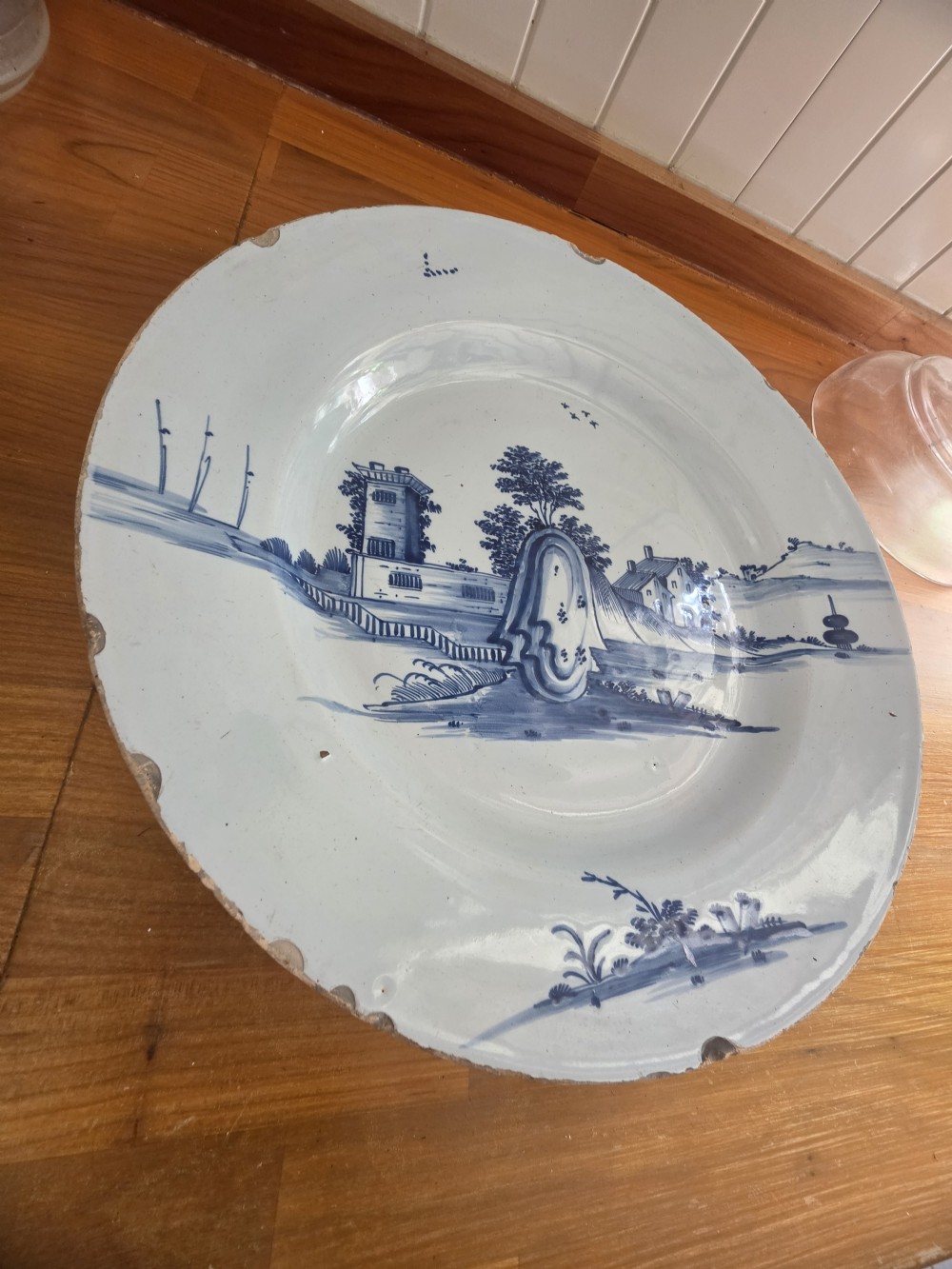 An 18th-century circular Bristol delftware charger plate featuring a hand-painted blue landscape scene on a white tin-glazed surface. View VI