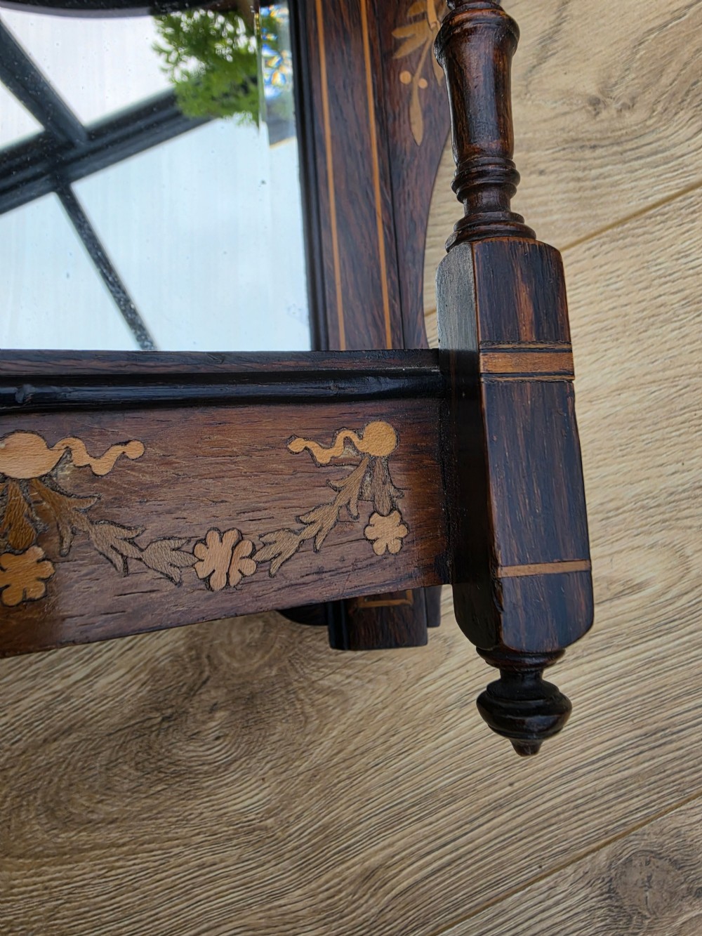 A dark mahogany wall mirror featuring light wood floral inlay, turned side columns, a shaped crest, and two integrated display shelves. View III