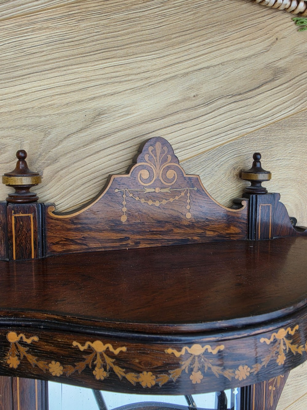 A dark mahogany wall mirror featuring light wood floral inlay, turned side columns, a shaped crest, and two integrated display shelves. View IV