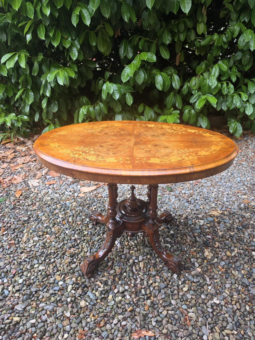 An oval 19th-century burr walnut centre table featuring floral marquetry inlay, supported by turned central columns and four carved legs. View VIII