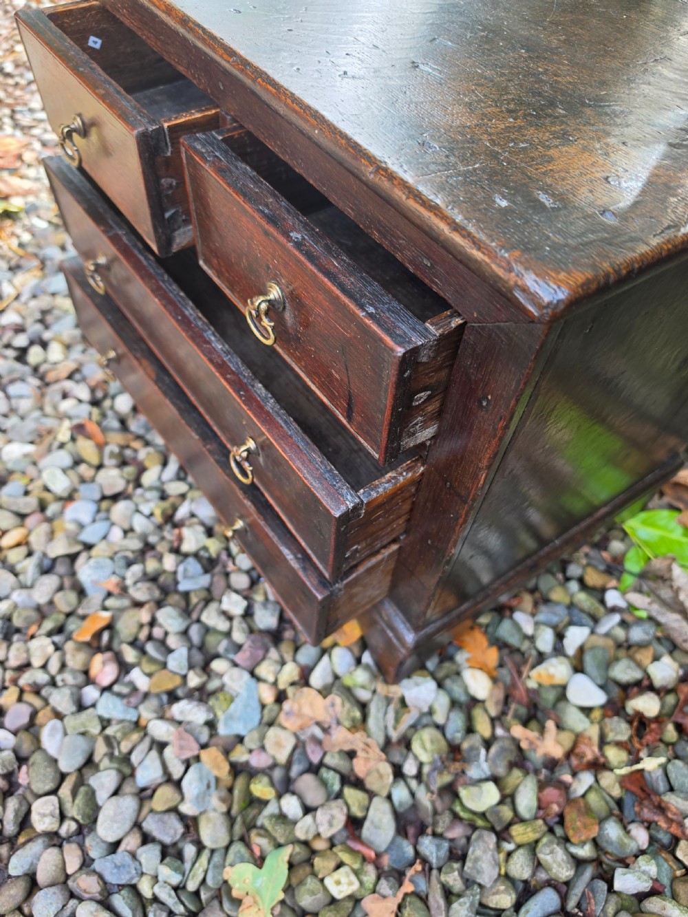 An 18th-century dark oak chest featuring two short drawers over two long drawers with brass drop handles, resting on bracket feet. View II