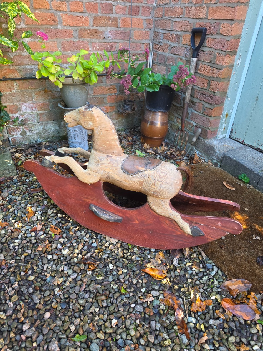 A 19th-century carved wooden rocking horse with visible grain, leather saddle detail, and a dark red painted bow rocker base. View VI