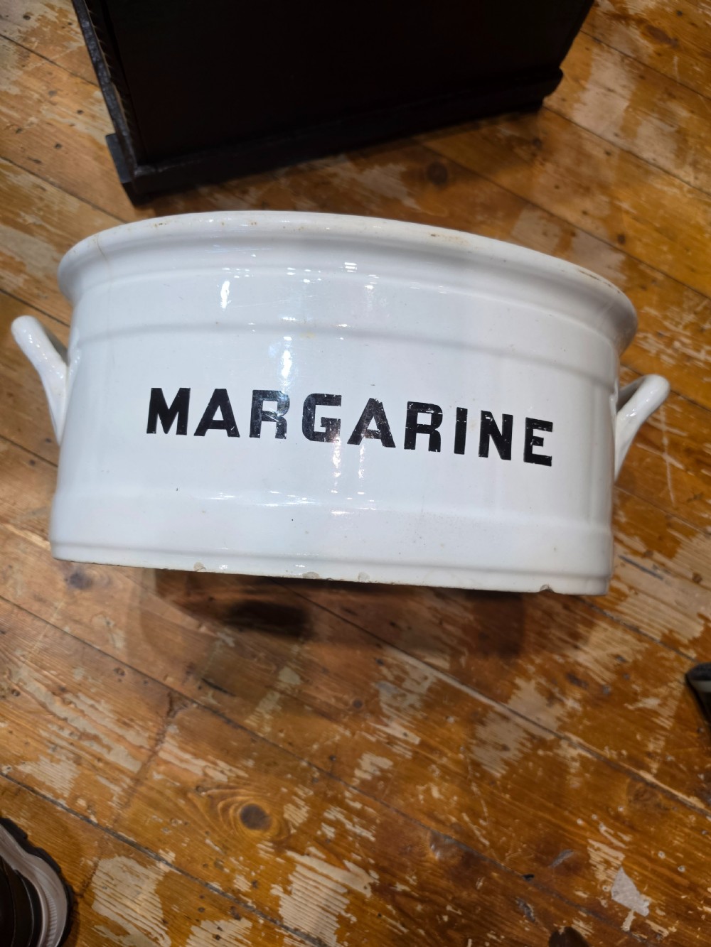 A white glazed ceramic oval tub with twin side handles, featuring bold black capital letters reading MARGARINE across the front.