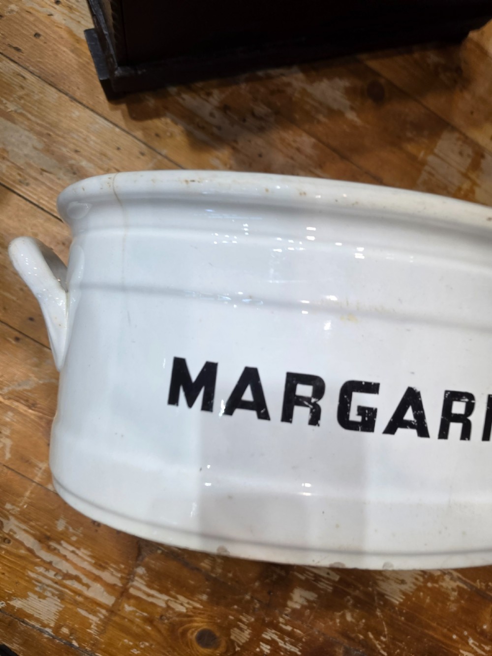 A white glazed ceramic oval tub with twin side handles, featuring bold black capital letters reading MARGARINE across the front. View II