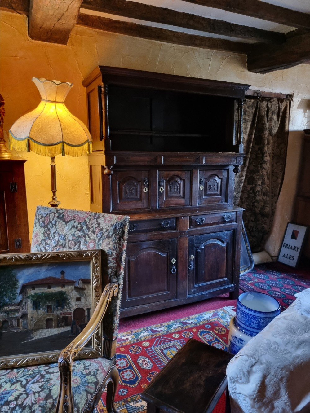 An eighteenth-century dark oak Welsh tridarn featuring a three-tiered structure with carved arched panels, turned pillars, and an inscribed date.