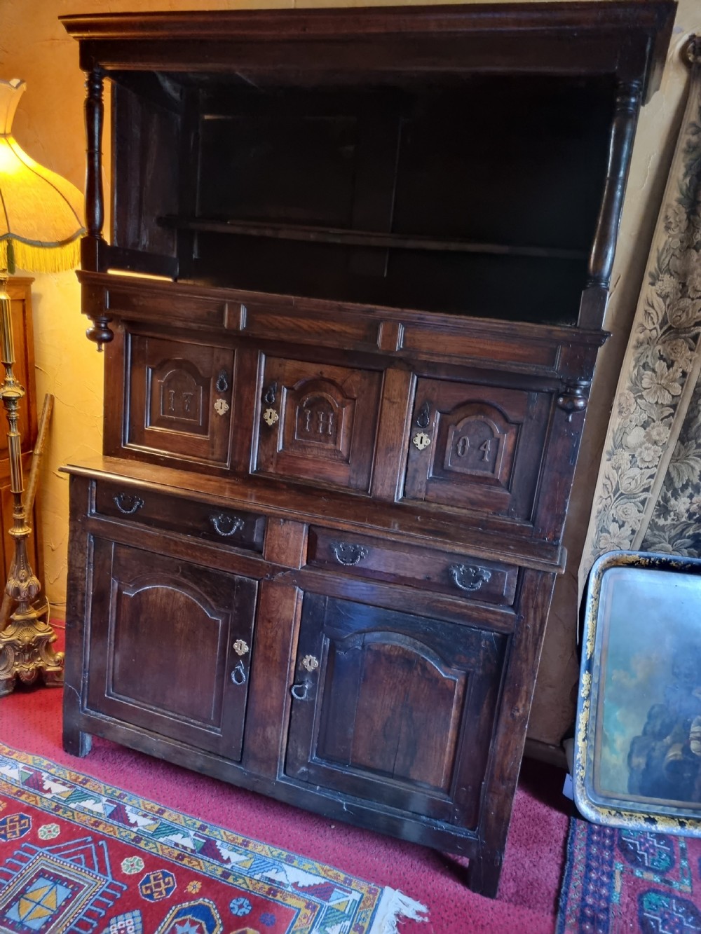 An eighteenth-century dark oak Welsh tridarn featuring a three-tiered structure with carved arched panels, turned pillars, and an inscribed date. View IV