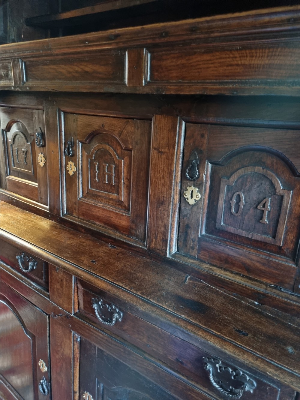 An eighteenth-century dark oak Welsh tridarn featuring a three-tiered structure with carved arched panels, turned pillars, and an inscribed date. View VI