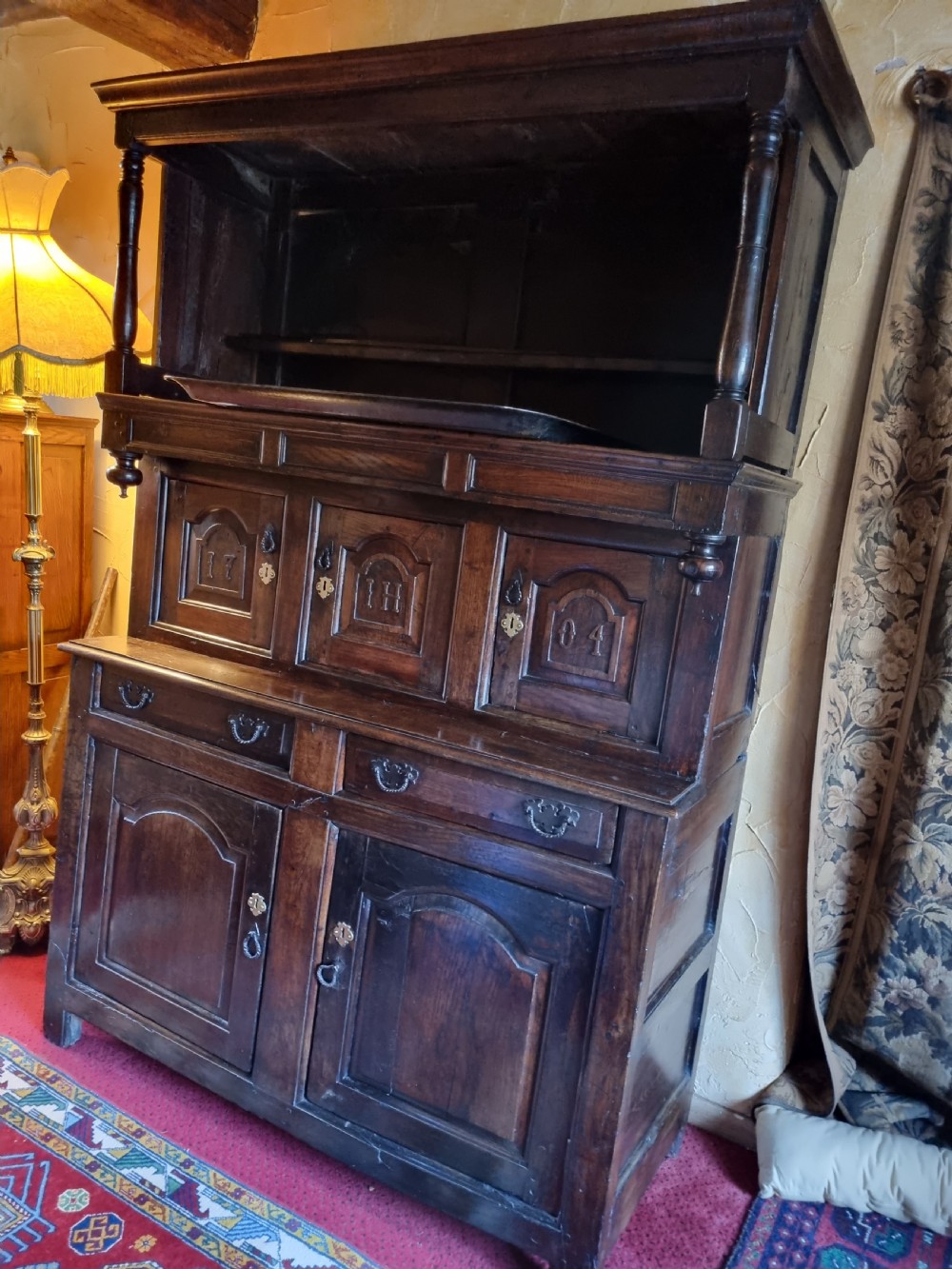 An eighteenth-century dark oak Welsh tridarn featuring a three-tiered structure with carved arched panels, turned pillars, and an inscribed date. View VII
