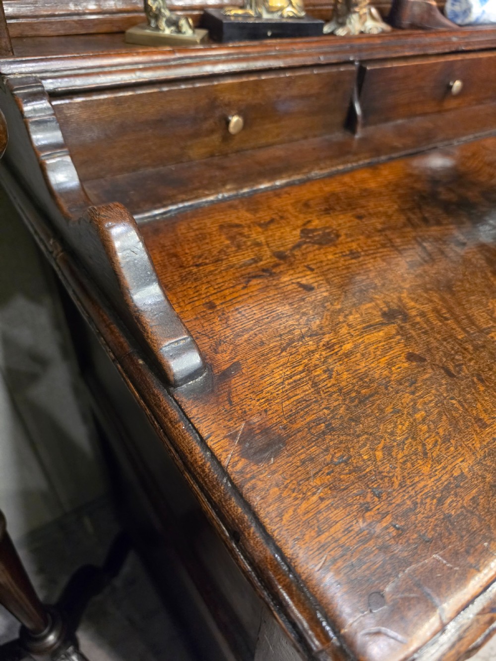 An 18th-century dark oak Welsh dresser featuring a three-tiered plate rack top above three drawers and three panelled cupboard doors with brass handles. View III