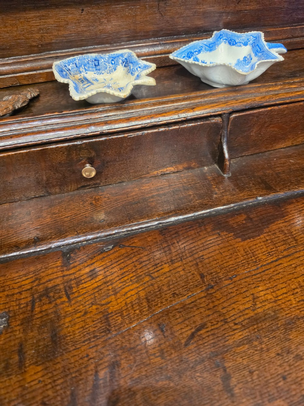 An 18th-century dark oak Welsh dresser featuring a three-tiered plate rack top above three drawers and three panelled cupboard doors with brass handles. View IV