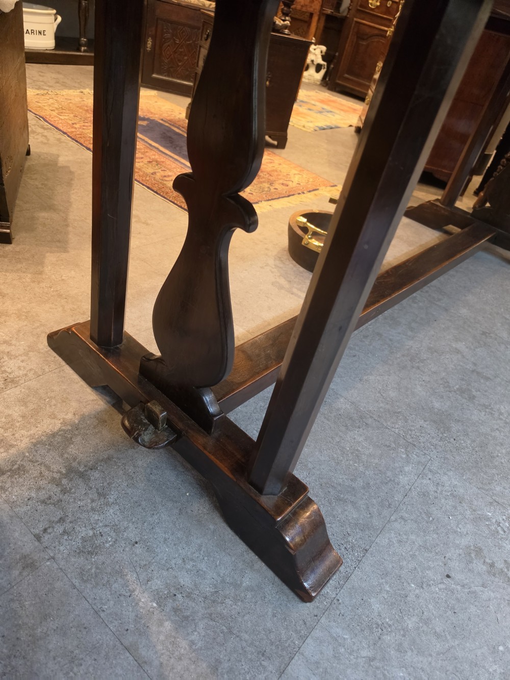A large 19th-century dark elm refectory dining table featuring a solid planked top supported by a trestle stretcher base. View VI
