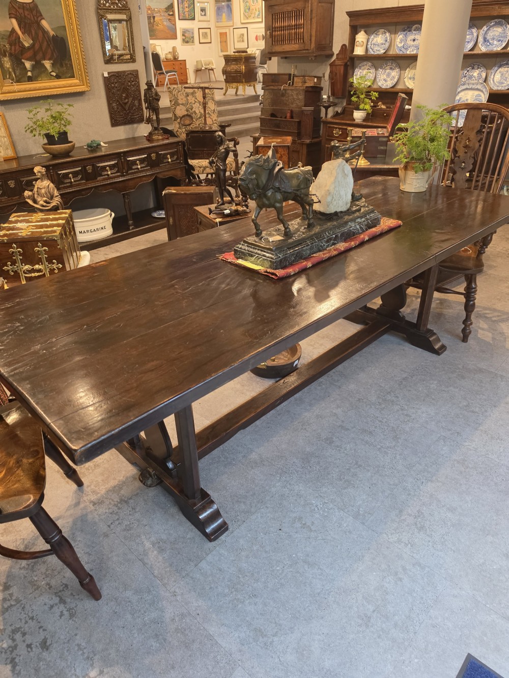 A large 19th-century dark elm refectory dining table featuring a solid planked top supported by a trestle stretcher base. View VII