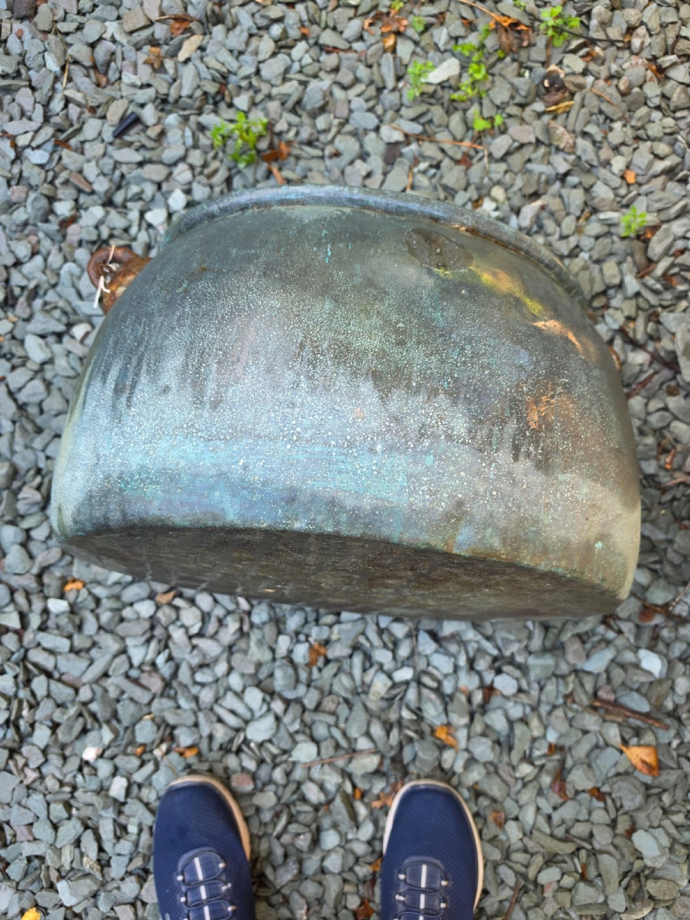 A large 19th-century copper cauldron with a rounded body, rolled rim, iron handles, and a verdigris patina.