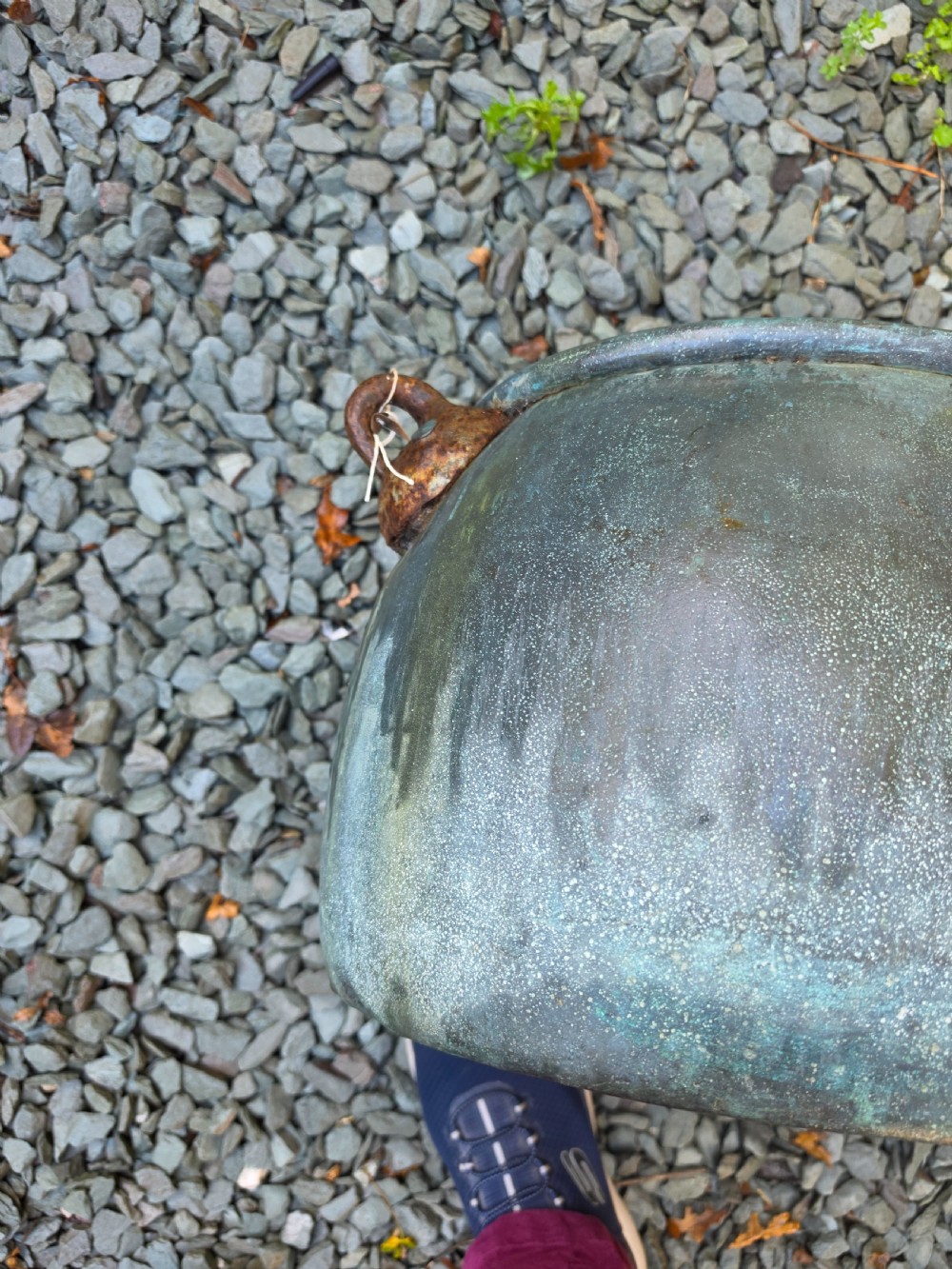 A large 19th-century copper cauldron with a rounded body, rolled rim, iron handles, and a verdigris patina. View V