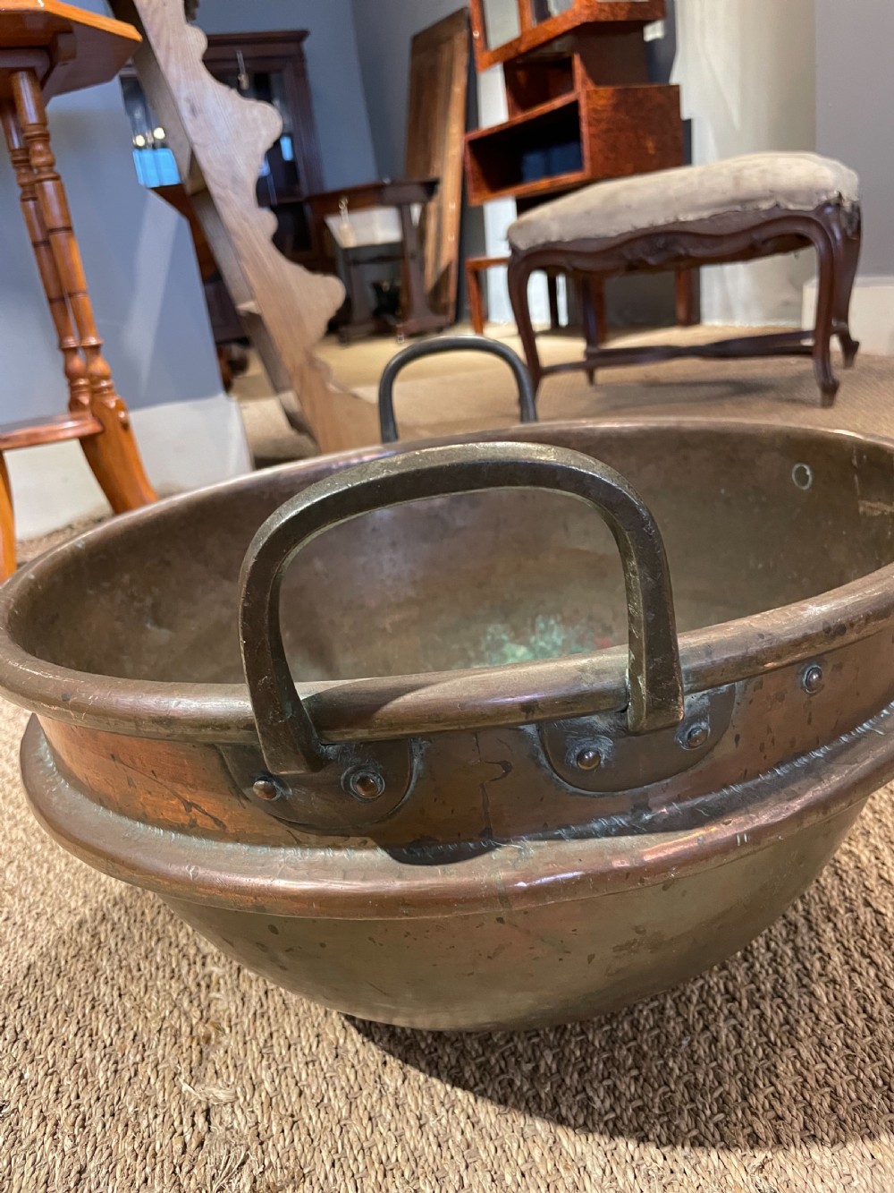 A round, hand-hammered antique copper pot with dual iron side handles and a weathered green patina on the interior base. View II
